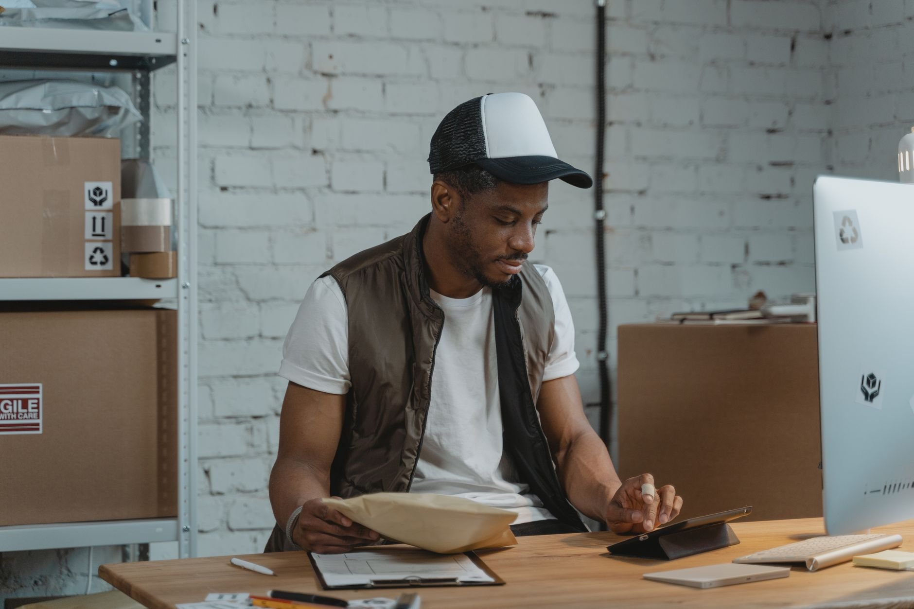 A man in a warehouse managing logistics orders with a tablet